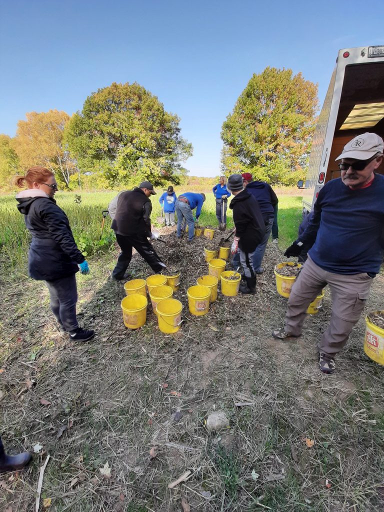 Thames Bluewater Métis Council members at a mulch pile, with multiple yellow buckets for carrying materials.